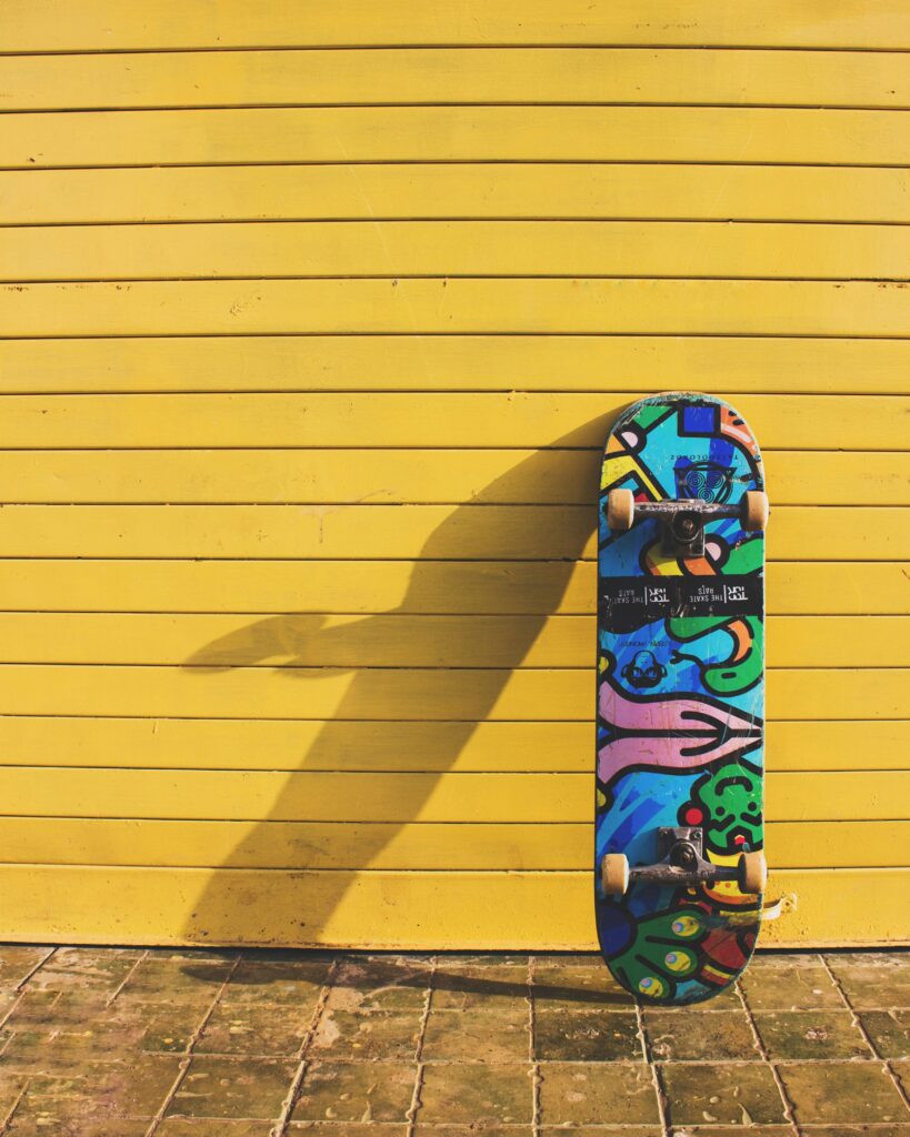 A colorful skateboard resting against a bright yellow wall, ready for a session