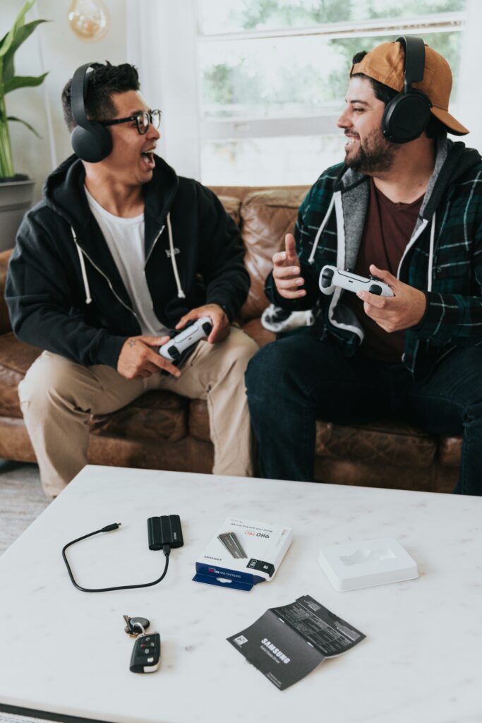 Two friends wearing headphones playing a video game with controllers